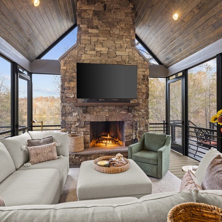 a living room with a stone fireplace and a deck